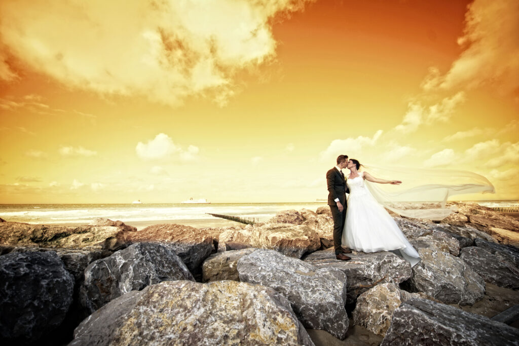 Couple de mariés sur la plage de Oye Plage au soleil couchant avec rochers